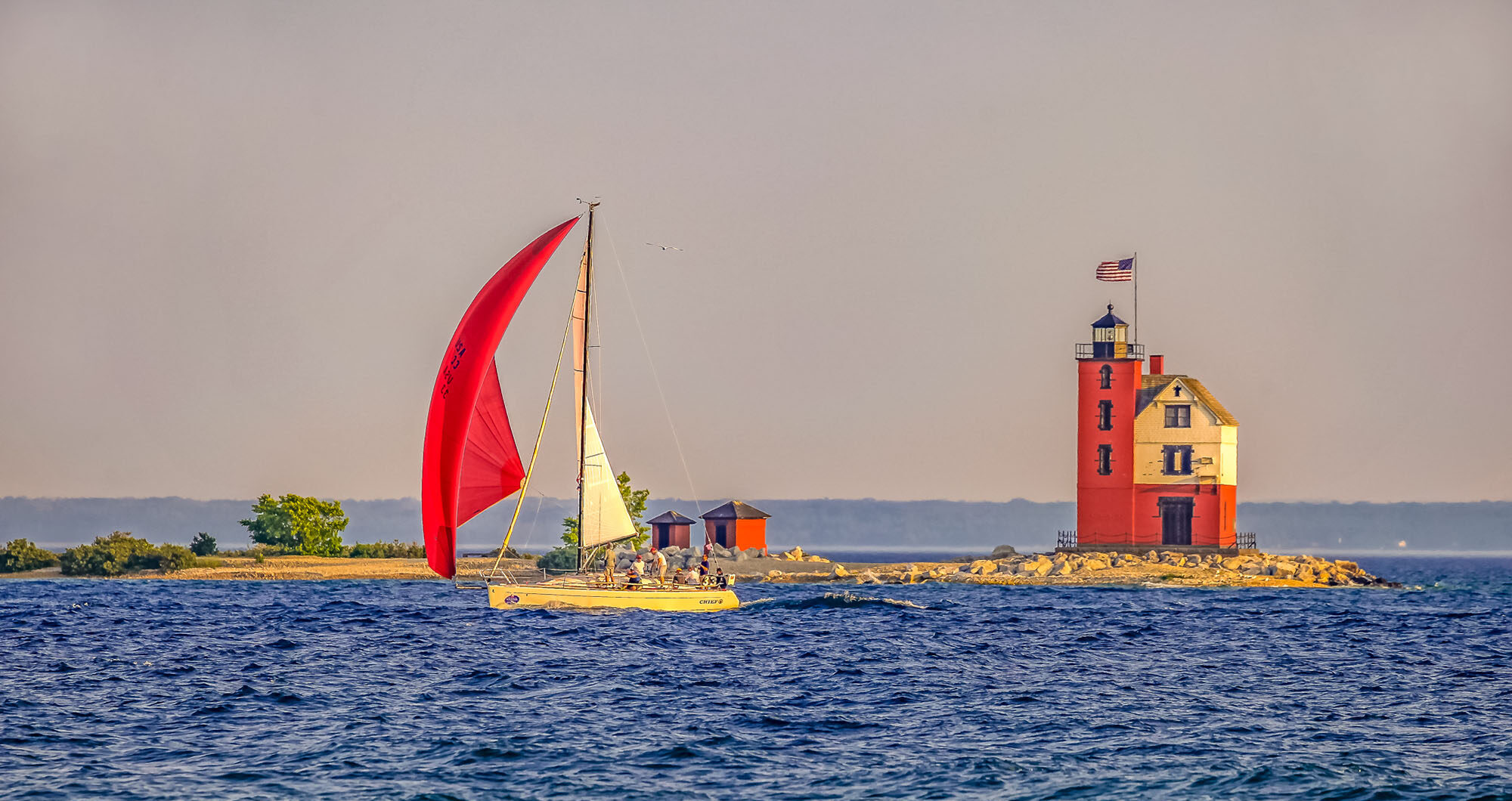 sail boats on the water by lighthouse